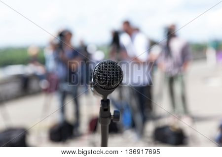 Microphone in focus against blurred camera operators. News conference.