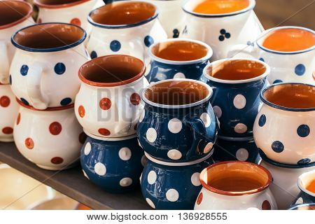 Colorful ceramic mugs hungarian polka-dotted hand painted handicraft pottery on sunny background