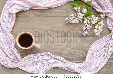 Pink cup with tea lilac and table-napkin on a wooden background. Focus is on the cup of tea. Copy space composition.