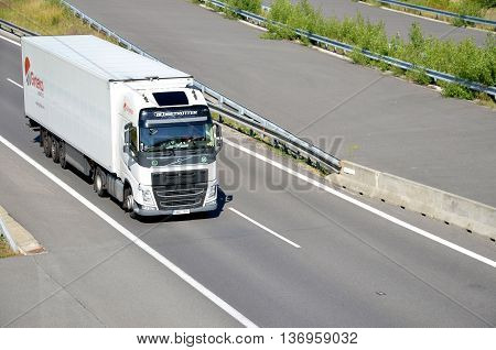 Dolny Hricov, Slovakia - June 29, 2016: White moving Volvo truck coupled with semi-trailer located on slovak D1 highway.