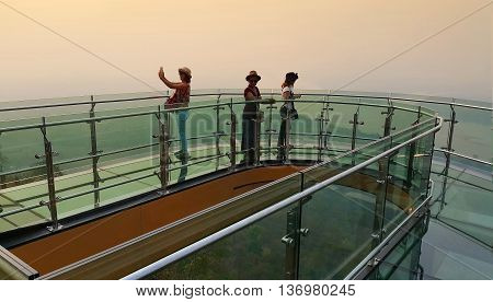 Nong Khai province Thailand- April 28 2016: Tourists walking and Selfie on transparent sky walk to see view of Mekong River during sunset at Wat Pha Tak Suea Sangkhom district Nong Khai province Thailand.