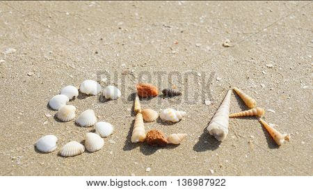 SEA word made of seashells on the sandy beach in Thailand.