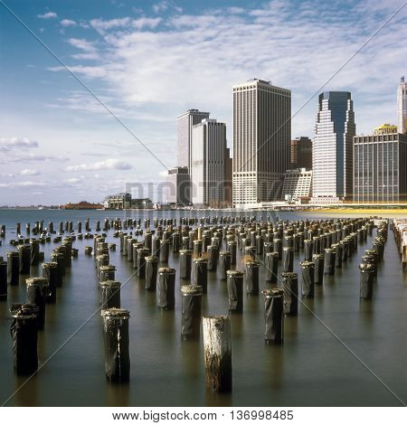 Old pier pylons and Downtown Manhattan New York City.