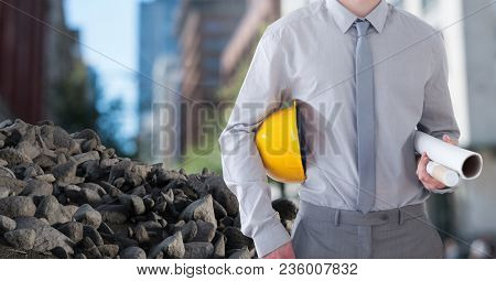 Rubble stones with Architect Construction worker holding helmet and blueprints in city