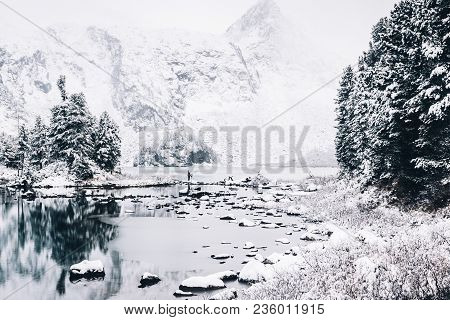 Mirror Surface Of The Winter Lake With A Mountain Range. First Snow In The Mountains. Travel To The