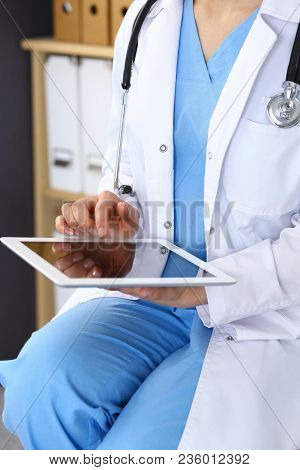 Woman Doctor Using White Tablet Computer While Working In Hospital.