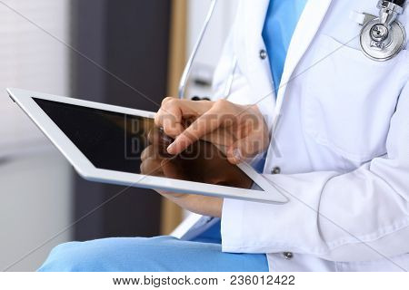 Woman Doctor Using White Tablet Computer While Working In Hospital.