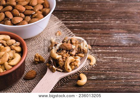 Differrent Variety Of Nuts - Walnuts, Cashew, Almond In Bowls And Wooden Spoon. Rustic Scratched Woo