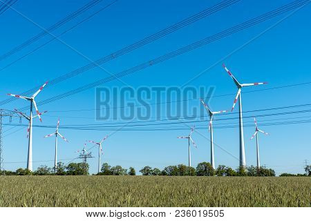 Wind Turbines And Power Supply Lines On A Sunny Day Seen In Germany