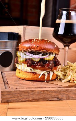Fresh Homemade Hamburger With Beef, Onion, Sause And Cabbage Garnish And Dark Beer On A Wooden Board