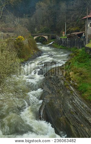 Beautiful Sinuous River With Brave Water And A Roman Bridge In The Background In The Gorbeia Natural