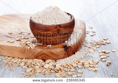 Heap Of Oat Flour In Wooden Bowl With Oat Flakes. Gluten Free Concept.