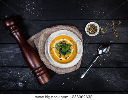 Pumpkin Soup With Jusai And Fried Cilantro, Served In White Bowl With A Spoon Linen Napkin And Peppe