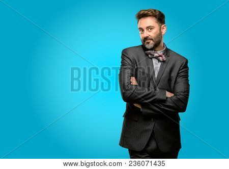 Middle age man, with beard and bow tie with crossed arms confident and happy with a big natural smile laughing