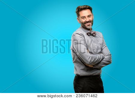 Middle age man, with beard and bow tie with crossed arms confident and happy with a big natural smile laughing