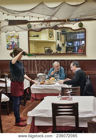 San Sebastian, Spain - March 28, 2018. Waitress Serving Txakoli To Customers. A Tipycal Wine With A 