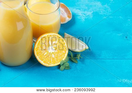 Orange Juice With Friuits And Minyt On Blue Wooden Table Close Up