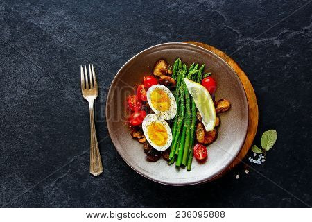 Flat-lay Of Healthy Vegetarian Breakfast Plate. Aspargus, Tomatoes, Mushrooms And Eggs Over Black St