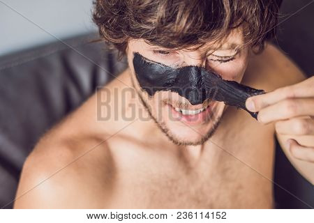 Happy Man With Black Mask On The Face. Photo Man Receiving Spa Treatments. Beauty Skin Care Concept.