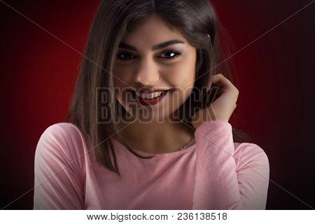 Brunette Woman In Pinc Dress With Long And Shiny Wavy Hair . Beautiful Model On Red Background. Stud