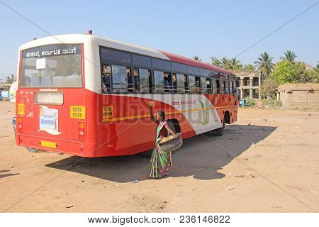 India, Hampi, 02 February 2018. A School Indian Bus Is On The Bus Station. A Girl Sells Food To Scho