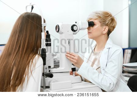 Backview Of Young Oculist Checking Patient's Vision.