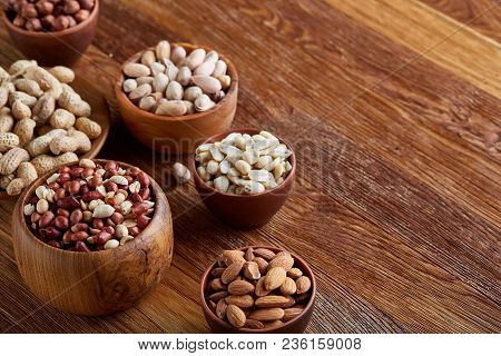 A Composition From Different Varieties Of Nuts In A Wooden Bowls Over Rustic Background: Hazelnuts, 
