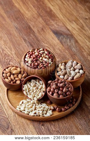 A Composition From Different Varieties Of Nuts In A Wooden Bowls Over Rustic Background: Hazelnuts, 
