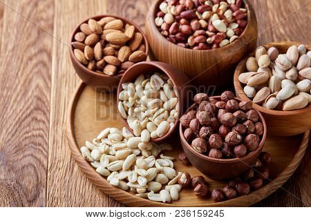 A Composition From Different Varieties Of Nuts In A Wooden Bowls Over Rustic Background: Hazelnuts, 