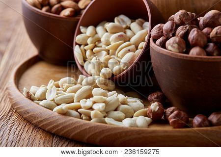 A Composition From Different Varieties Of Nuts In A Wooden Bowls Over Rustic Background: Hazelnuts, 
