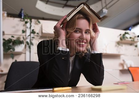Side View Image Of Smiling Businesswoma With Book On Head. Making Fun After Work.