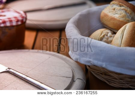 Basket Of Freshly Baked Dinner Rolls With Tableware In Background. Close Up