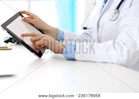 Woman Doctor Using Tablet Computer While Sitting At The Desk In Hospital Closeup. Cardiologist Check
