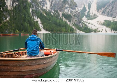 The Guy Is Sitting In A Boat And Starts To Row, Against Lake La-go Di Brize