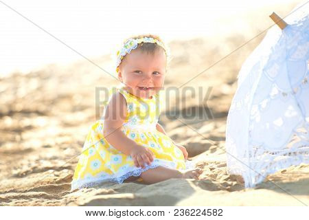 Lovely Little Girl On The Beach With An Umbrella.