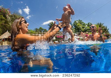 Funny photo of  happy active family young mother with active baby diving in swimming pool with fun jump . 