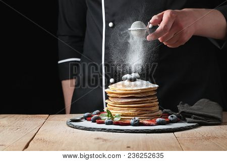 Serving Pancakes With Powdered Sugar And Berries. Chef Man Hand. Beautiful Food Still Life. Slightly