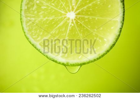 Close-up Of A Slice Of Lime, A Drop Of Water Falls. The Fruit Gives Off Freshness And Juice Filling.