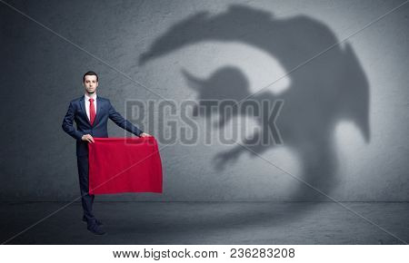 Businessman standing with red cloth in his hand and imp shadow on the background