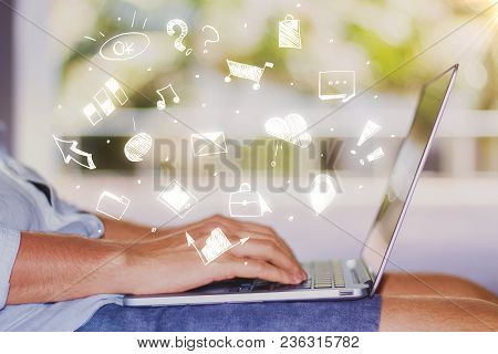 Side View Of Young Man Using Laptop Placed On His Lap. Blurry Outdoor Background With Social Media S