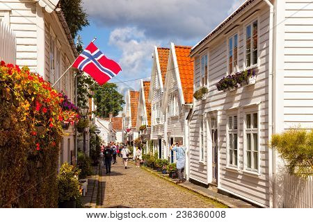 Stavanger, Norway - August 01, 2017: Tourists Walking A Short Street With Small Old Wooden Home. Sta