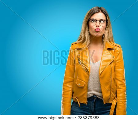 Beautiful young woman making funny face fooling, blue background