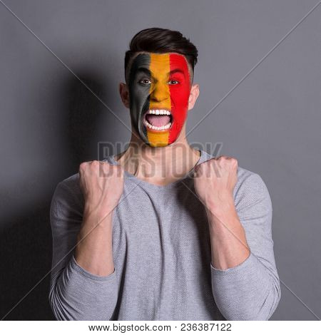Portrait Of Happy Man With The Flag Of Belgium Painted On His Face. Football Or Soccer Team Fan, Spo