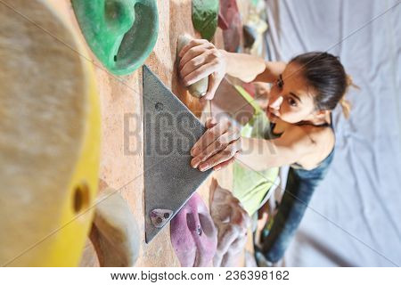 Workout Exercise. Top View Of A Woman Climber Climbs Indoors In Bouldering Gym. Young Woman Climbing