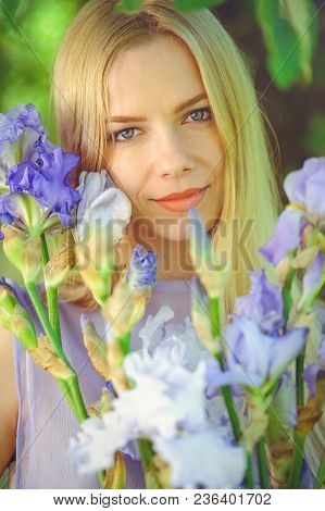 Attractive Young Girl With Blonde Dren Hair And Natural Make-up Smelling Blue Purple Iris Flowers On