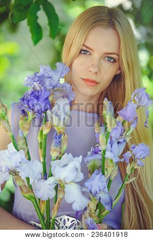 Attractive Young Girl With Blonde Dren Hair And Natural Make-up Smelling Blue Purple Iris Flowers On