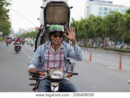 Ho Chi Minh City, Vietnam 21.03.2018 - Asian Man Is Waving T O The Camera While Driving Motorbike Wi