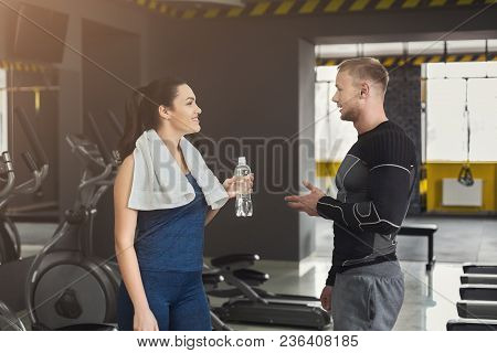 Fitness Couple Having Rest, Drinking Water At Gym. Smiling Man And Woman With Plastic Bottle, Talkin