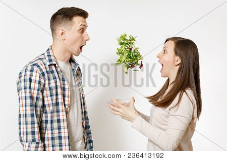 Fun Couple Man Woman Standing And Throwing Up Salad From Glass Bowl Isolated On White Background. Pr
