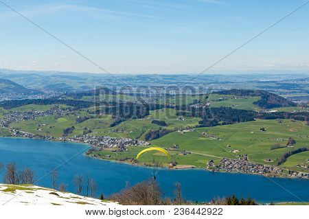 Beautiful Nature View In Swiss Alps With Paraplane Flying Over The Lake